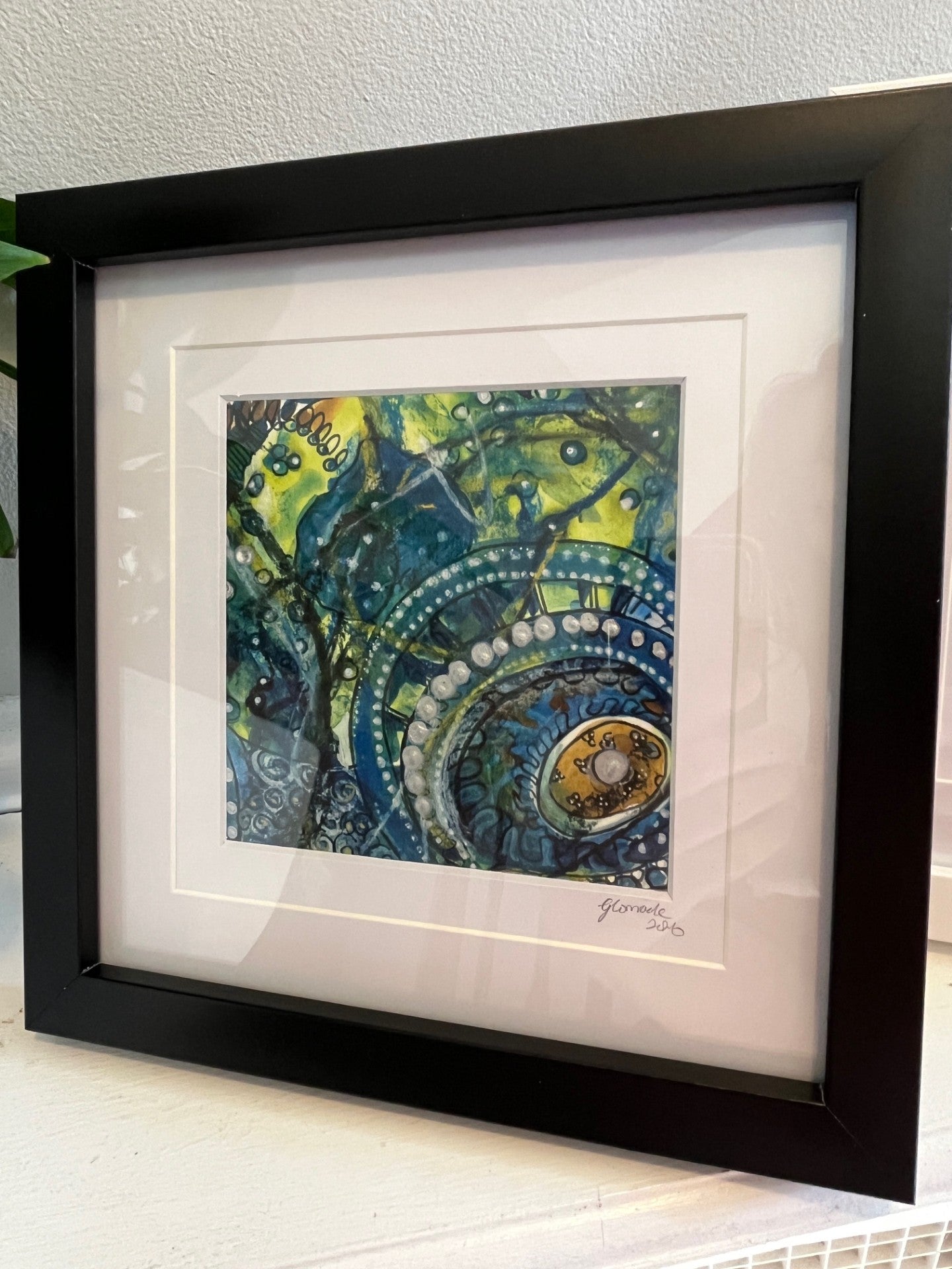 Framed abstract artwork with black frame on a white surface