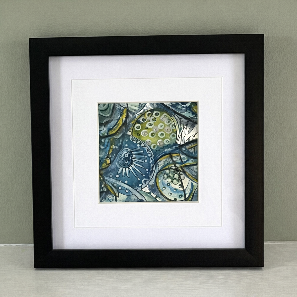 Framed abstract artwork with blue and green patterns on a plain background