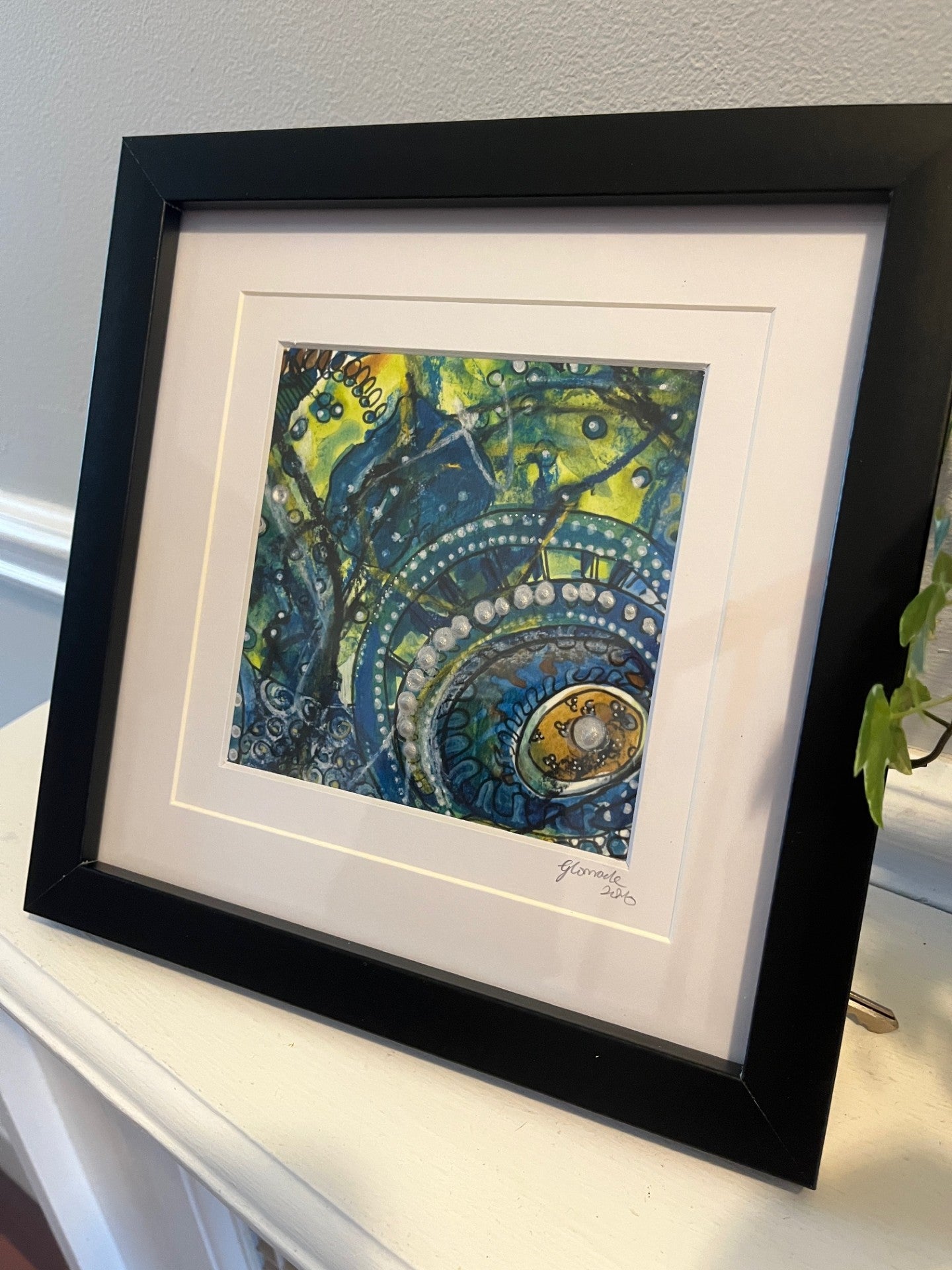 Framed abstract artwork with black frame on a white surface